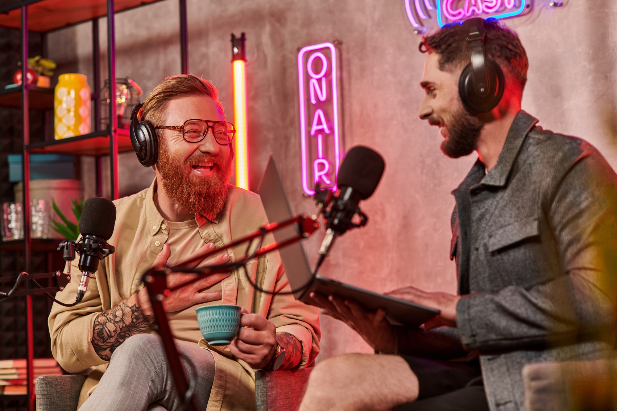 attractive jolly men in casual attires with coffee and laptop during their discussion on podcast