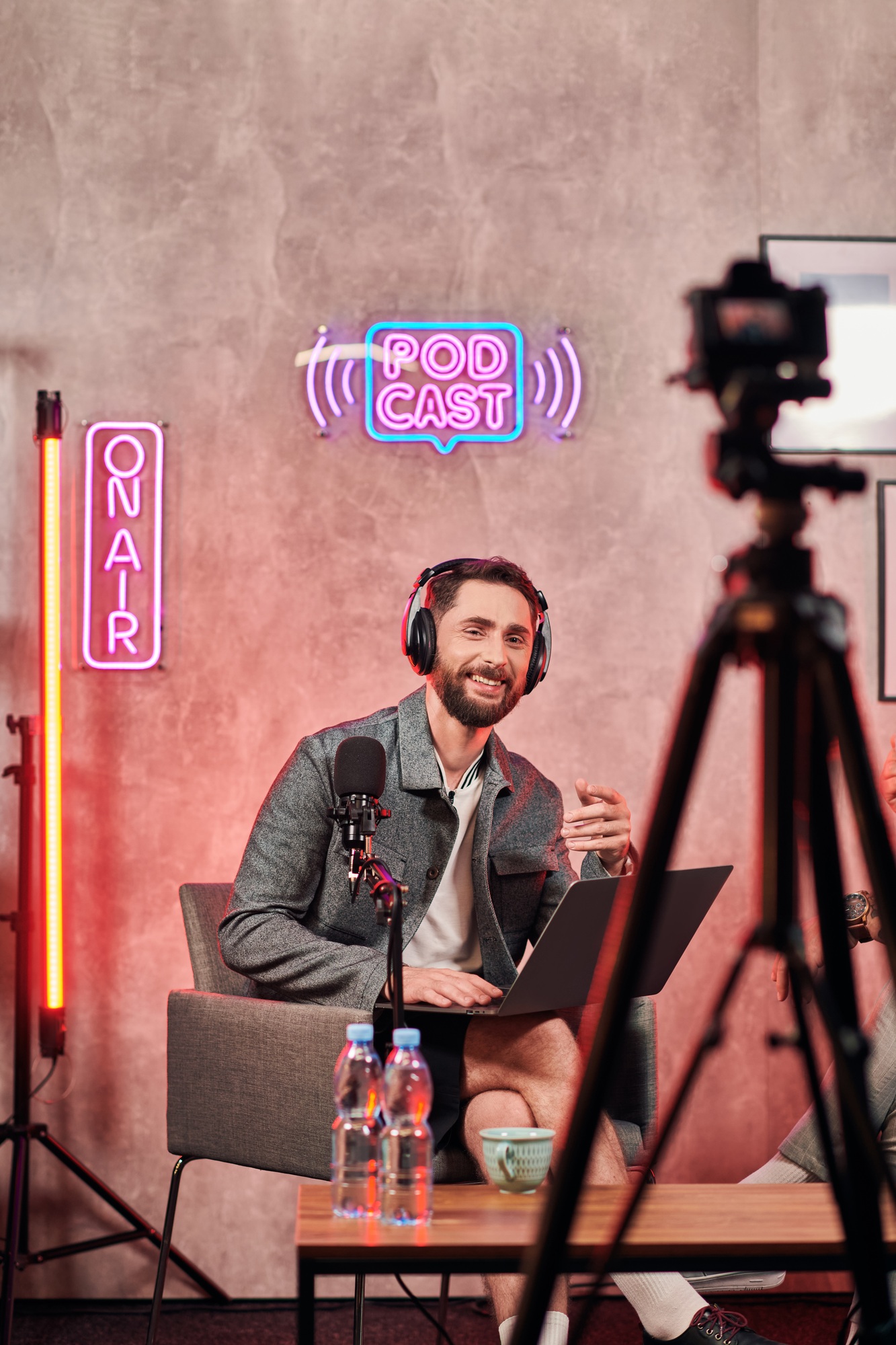 cheerful bearded man in casual comfy attire sitting with laptop during podcast looking at camera