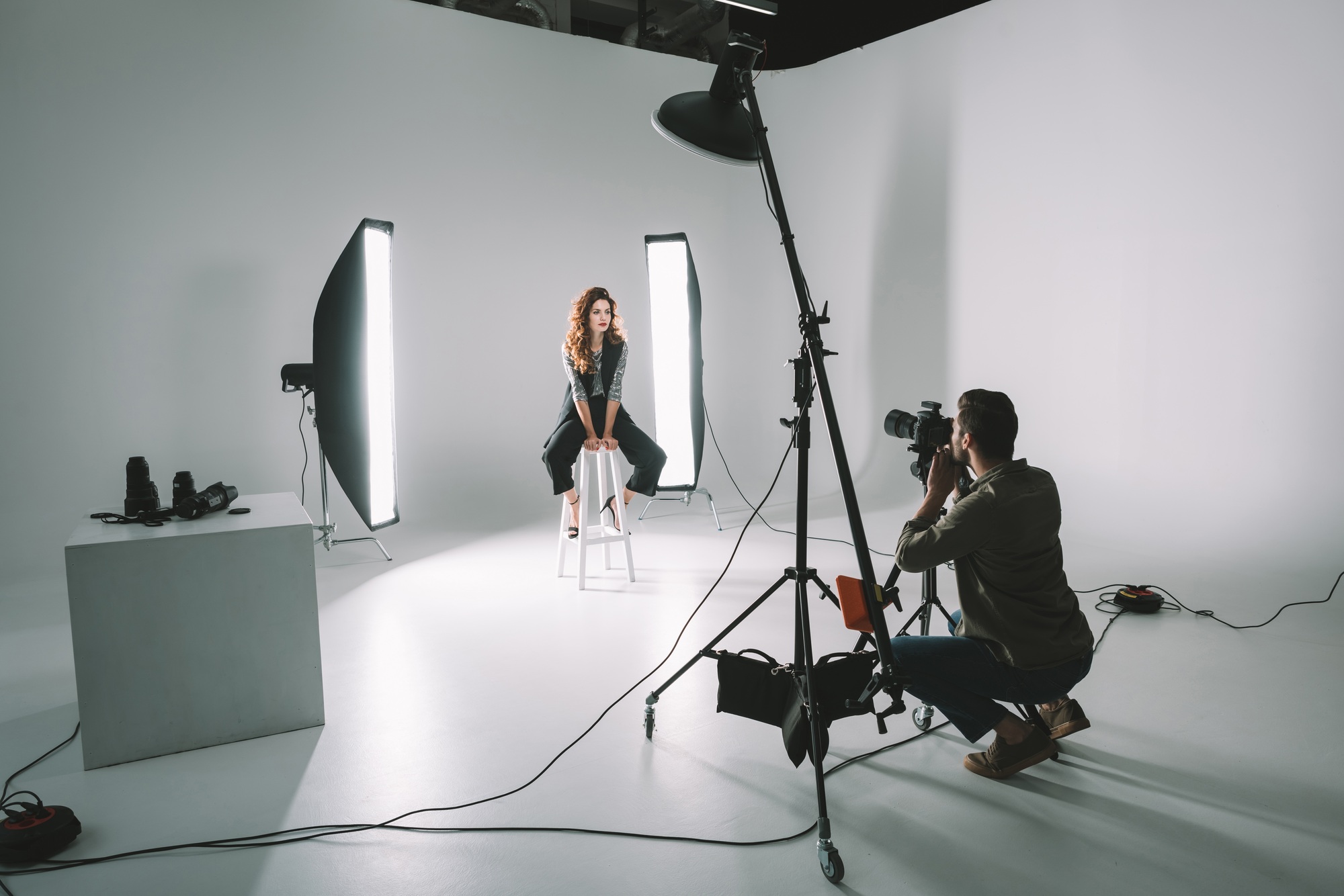 professional photographer and beautiful model on fashion shoot in photo studio with lighting